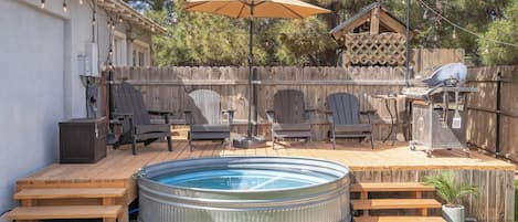 Un jardin avec un jacuzzi, des chaises longues et un barbecue.