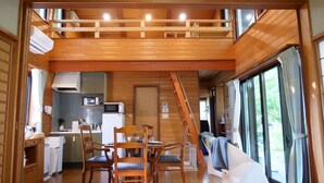 A wooden cabin interior with a dining area, kitchen, and a loft bedroom. - Forest Villa Yamanakako (Yamanakako)