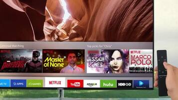 En tv-skärm som visar Netflix användargränssnitt med olika program, och en fjärrkontroll i handen.
