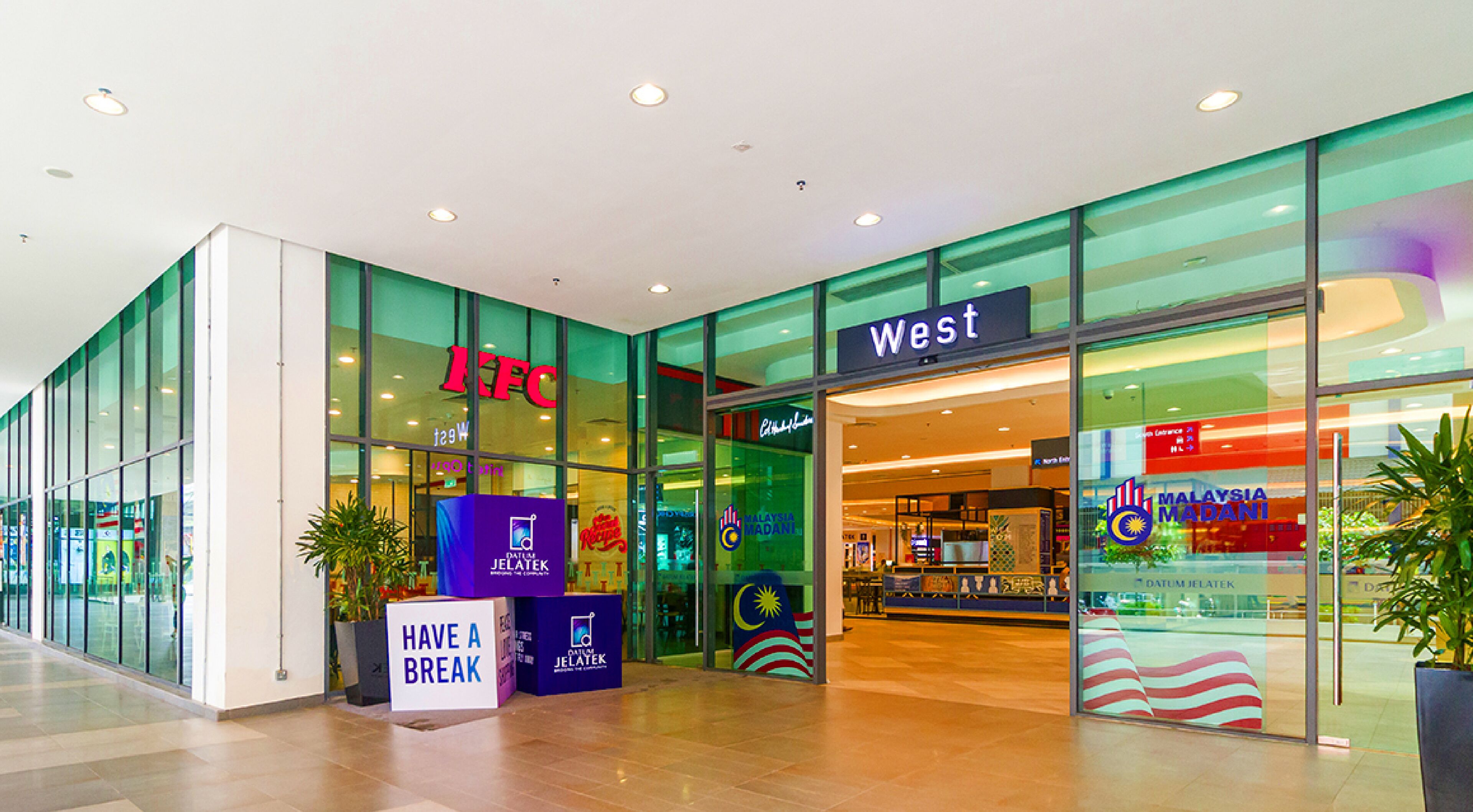 A KFC and West store entrance with glass walls, a 'Have a Break' sign, and Malaysia Madani signage.