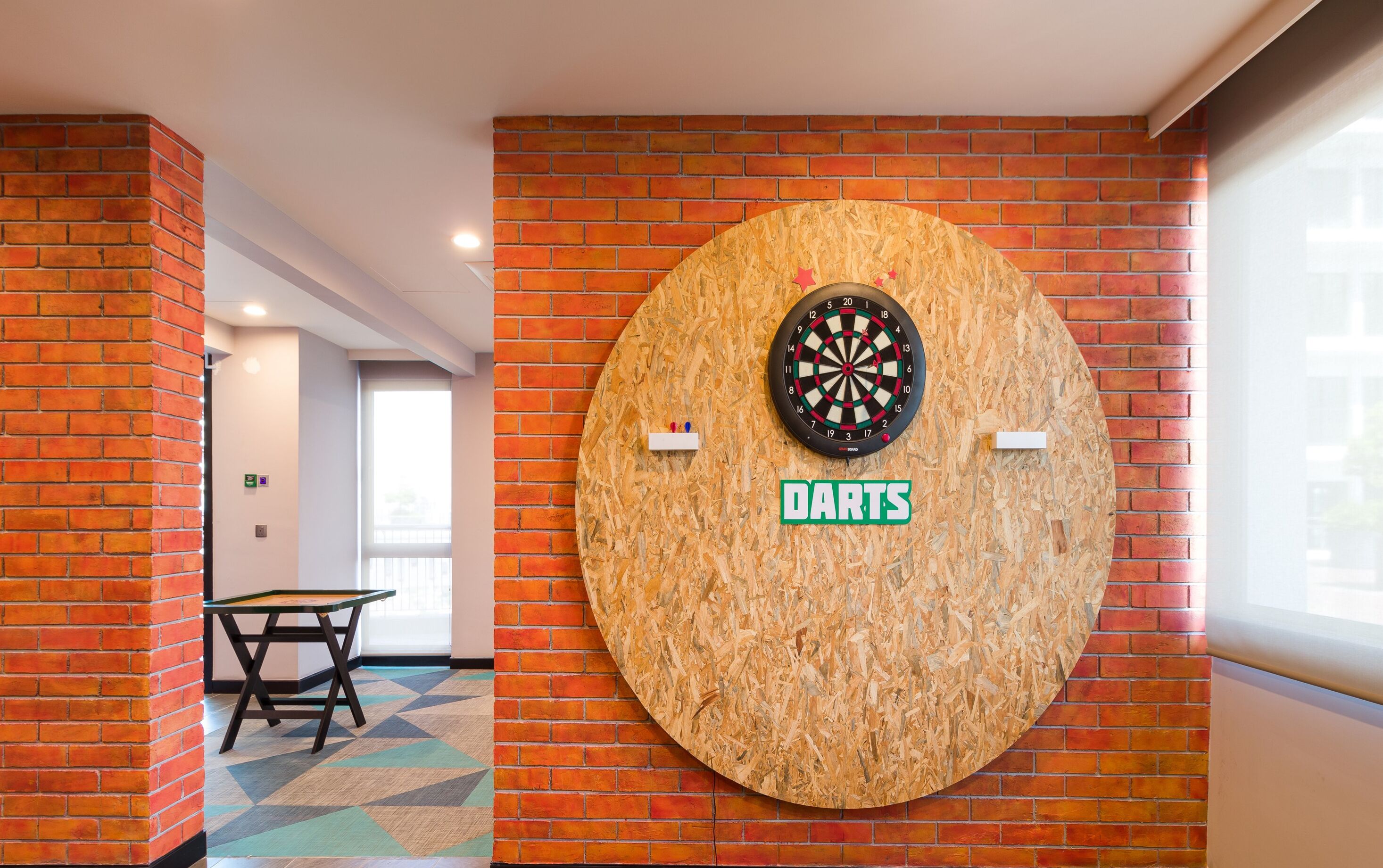 A dartboard mounted on a brick wall with a "DARTS" sign below it.