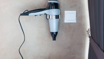 Un secador de pelo fijado a una pared color beige, con un enchufe cerca.