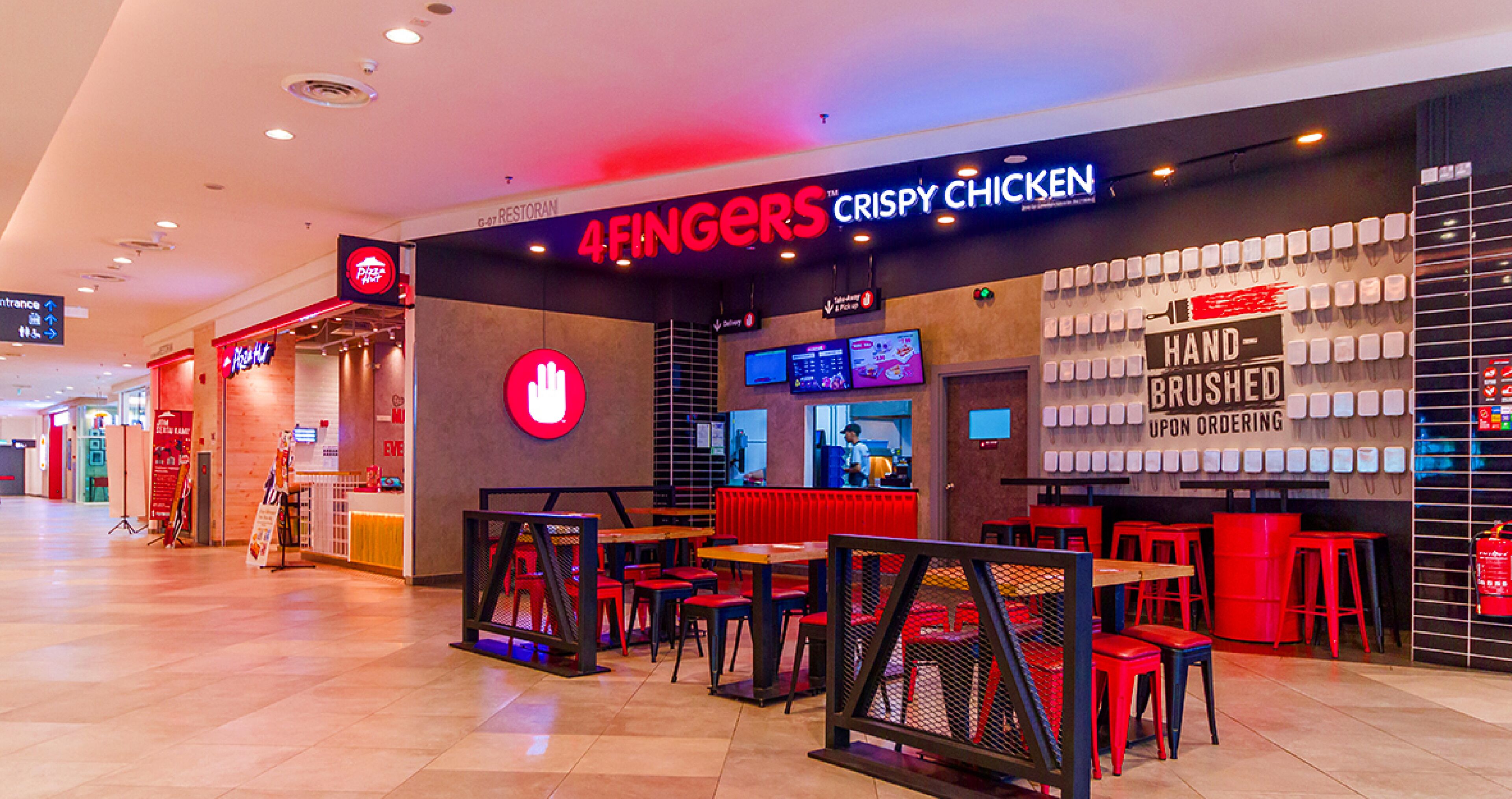 A 4Fingers Crispy Chicken restaurant with red and black decor, multiple seating areas, and a digital menu display.