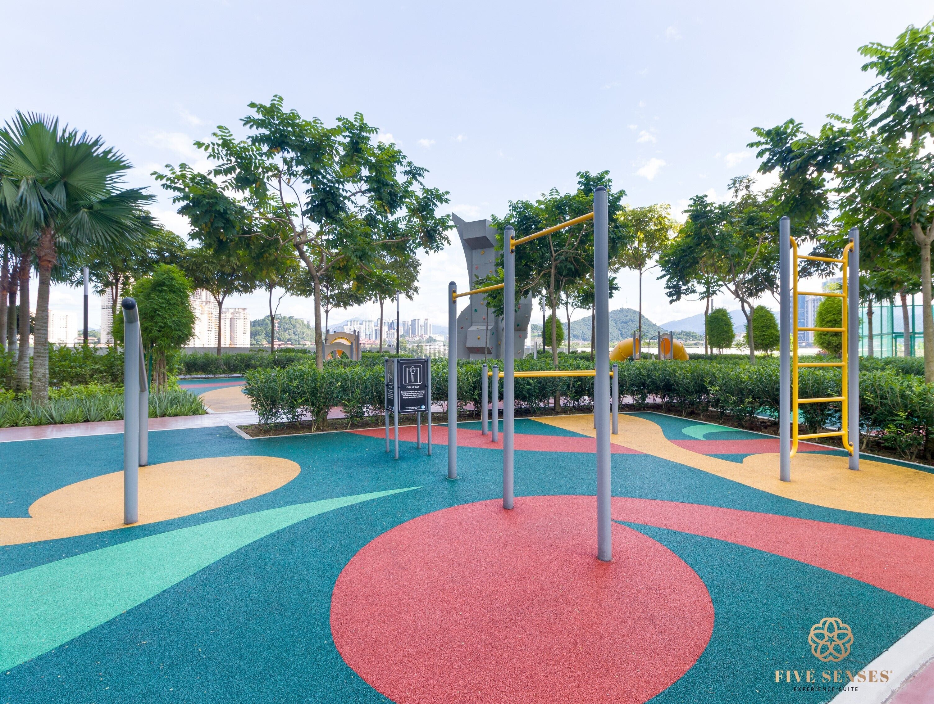 A playground with colorful rubber flooring, climbing structures, and a yellow slide.