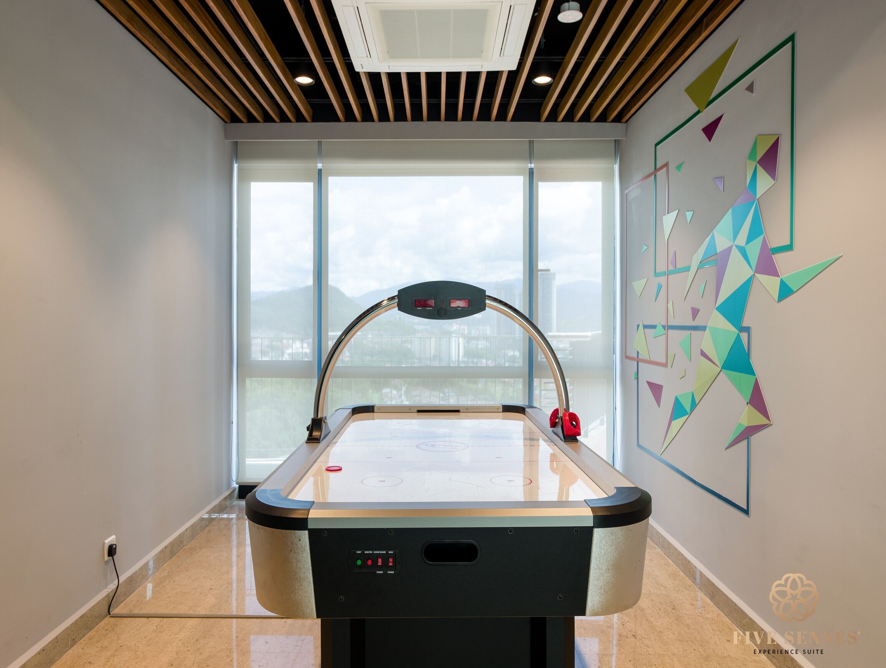A pool table in a room with large windows, a ceiling with wooden slats, and a geometric wall decoration.