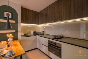 A modern kitchen with wooden cabinets, a stainless steel oven, and a wooden dining table with a vase of flowers.