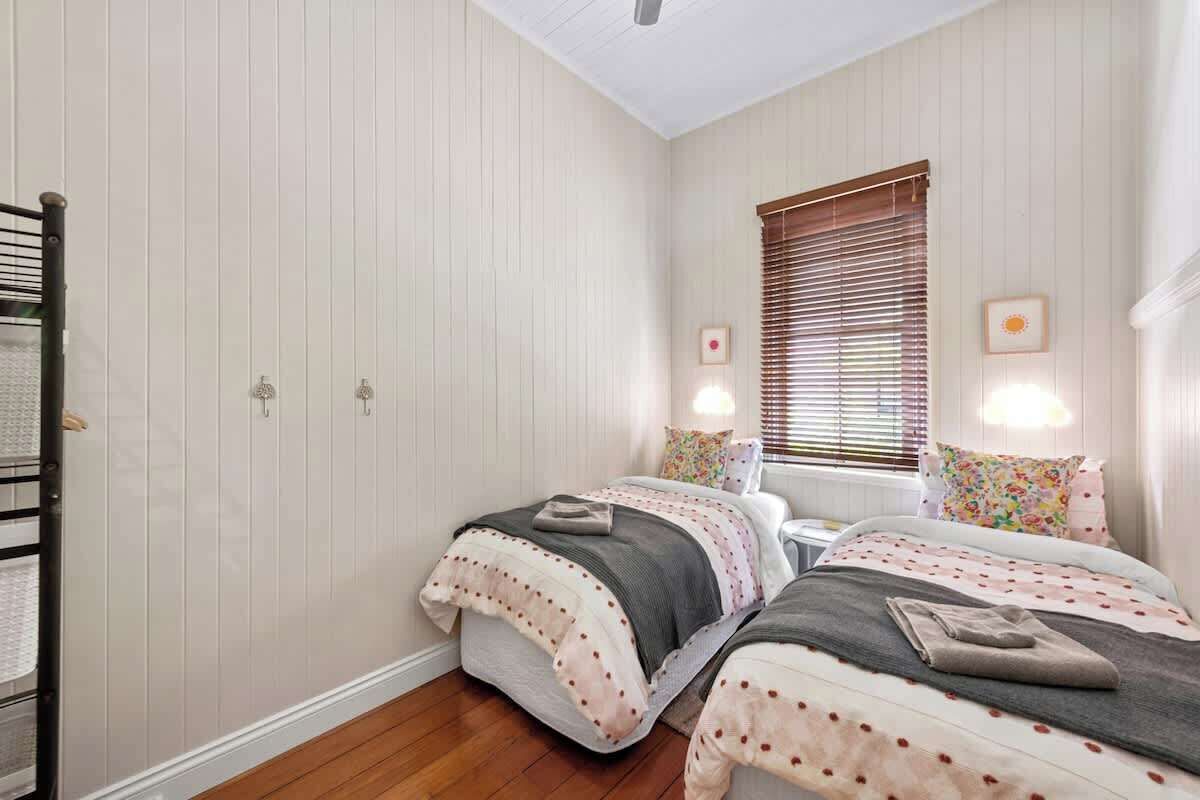 A bedroom with two beds, a wardrobe, and a window with blinds.