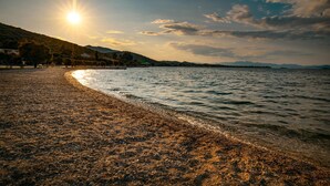 Ein Kiesstrand mit Blick auf das Meer und ferne Berge.