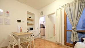 Un espace de vie compact comprenant un coin repas, une kitchenette et une chambre.