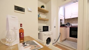 Une cuisine compacte équipée d’un four à micro-ondes, d’un four traditionnel et d’un lave-linge.