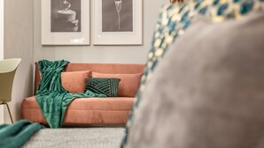 Een kamer met een bank, een groene plaid en twee ingelijste foto's aan de muur.