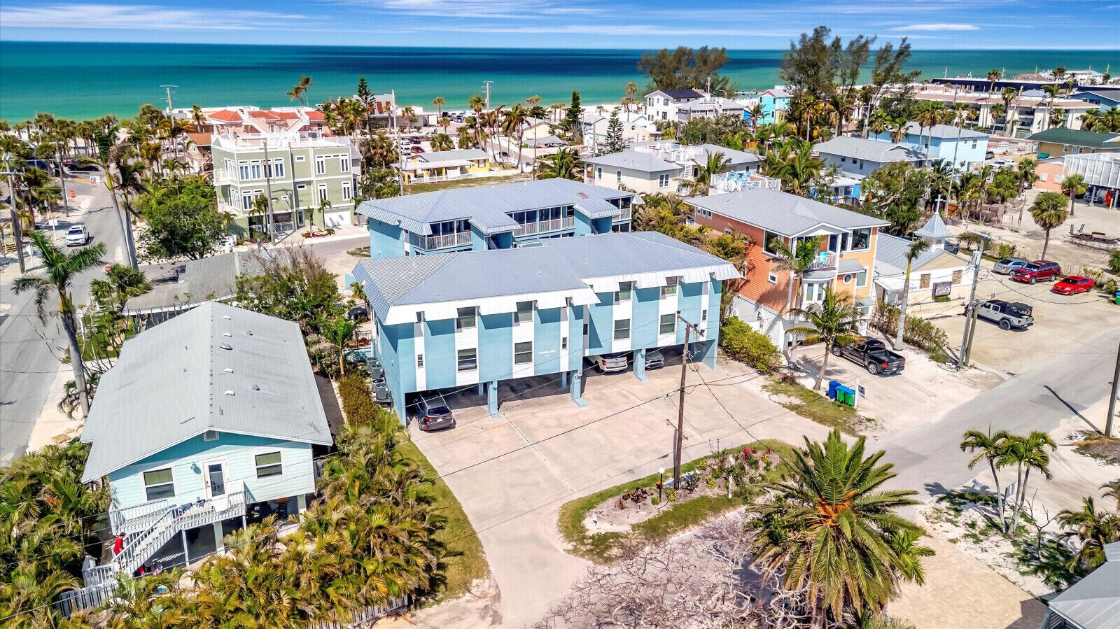 A coastal residential area with a prominent blue building, likely a hotel, featuring a flat roof and multiple windows.