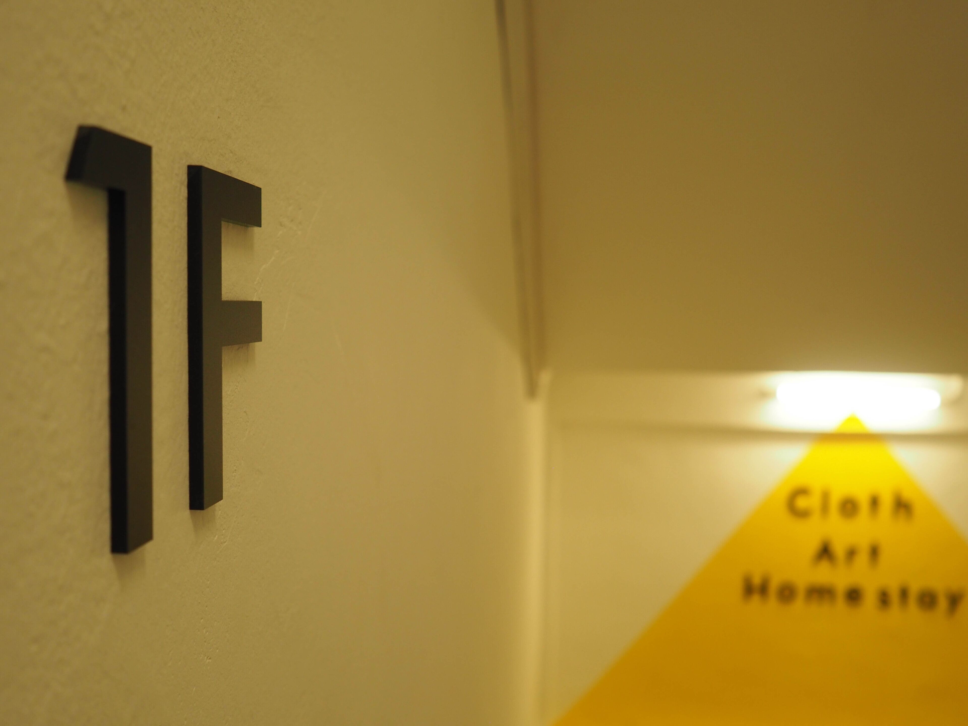 A hallway with a sign reading "Cloth Art Home Stay" and a number sign "1F".