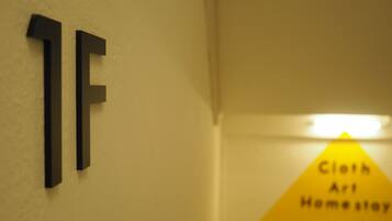 A hallway with a sign reading "Cloth Art Home Stay" and a number sign "1F".