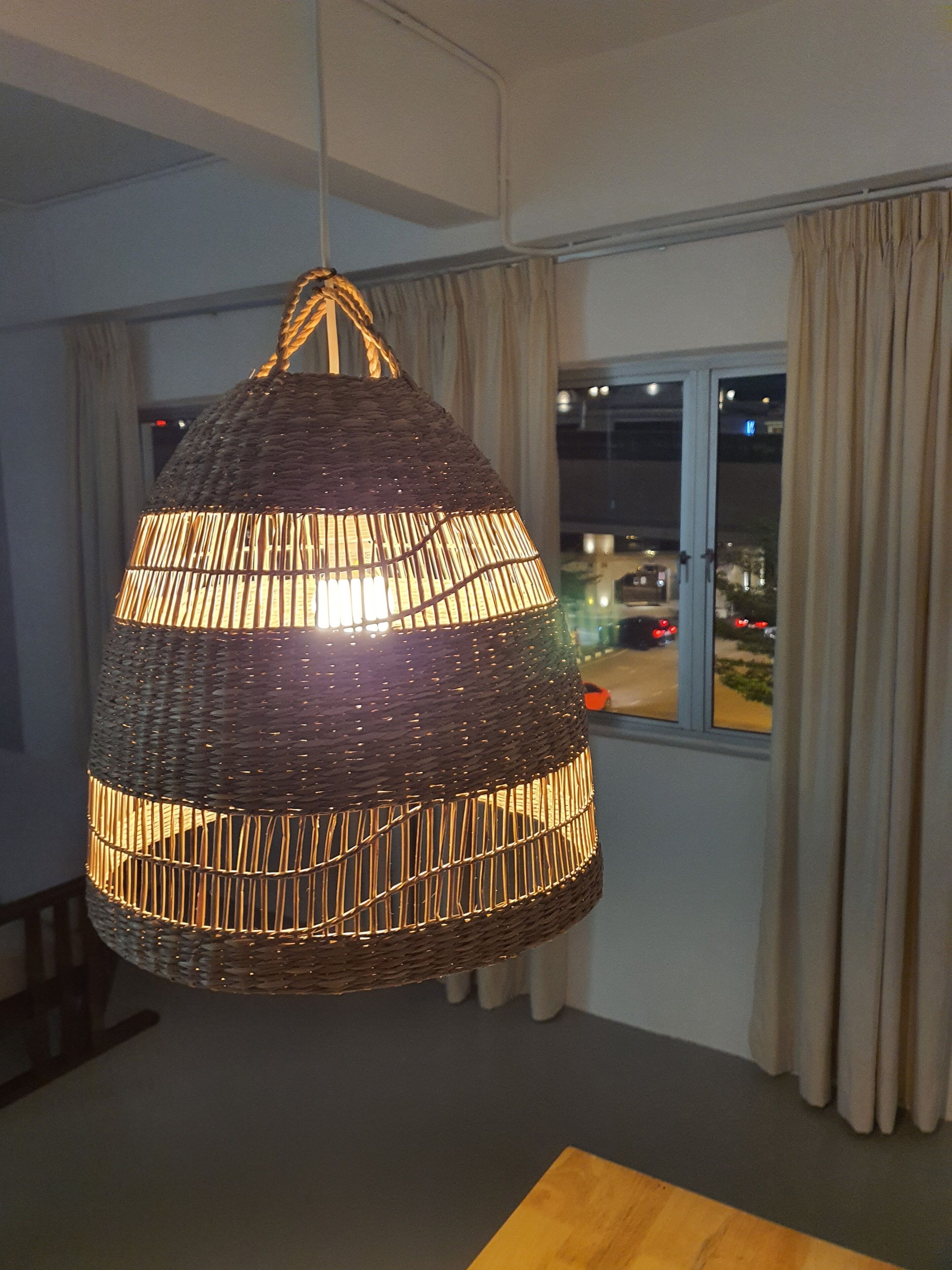 Lámpara colgante de tejido en una habitación con vista a la calle a través de una ventana.