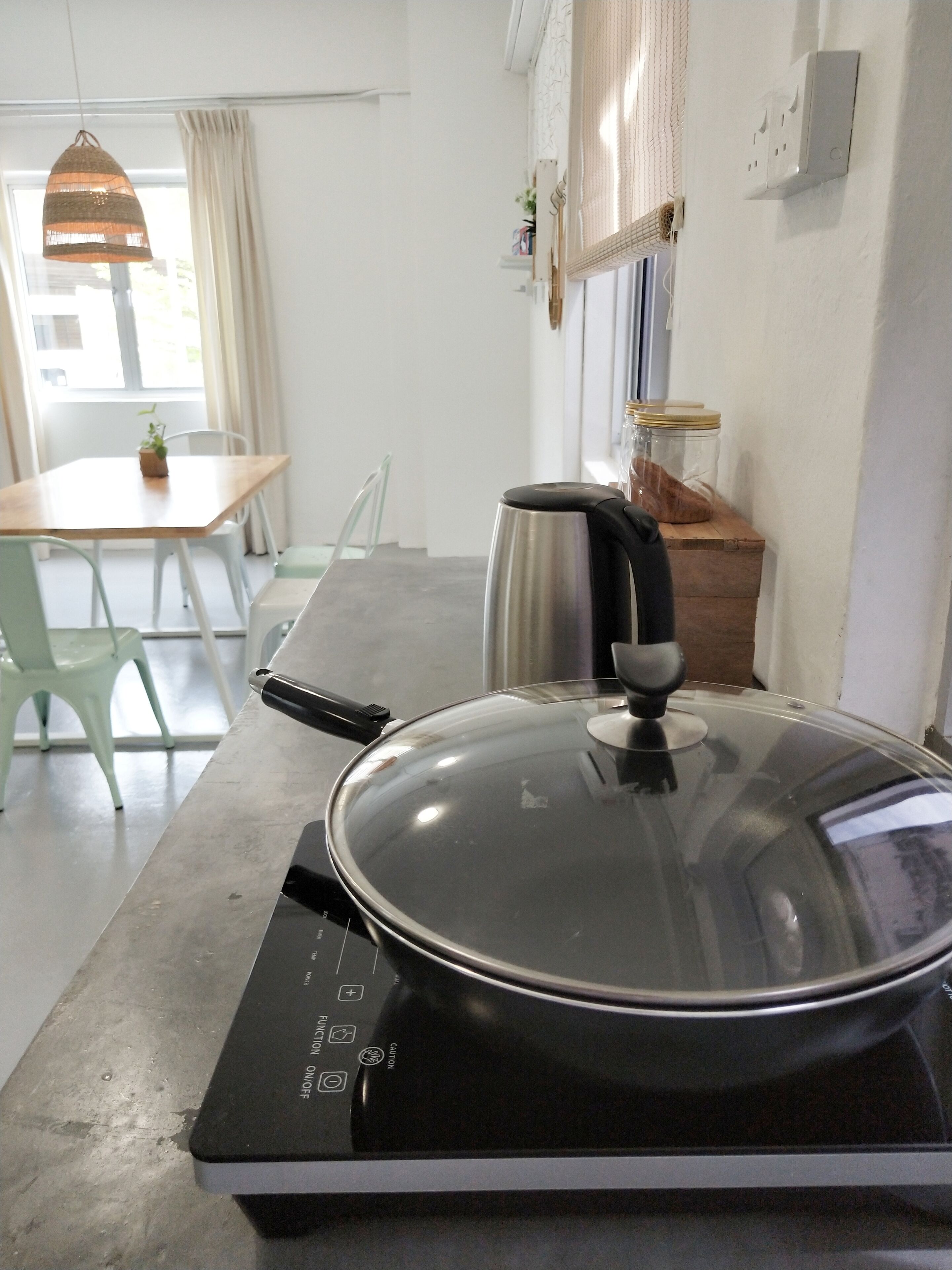 Una cocina con estufa, una mesa con sillas y una lámpara colgante.