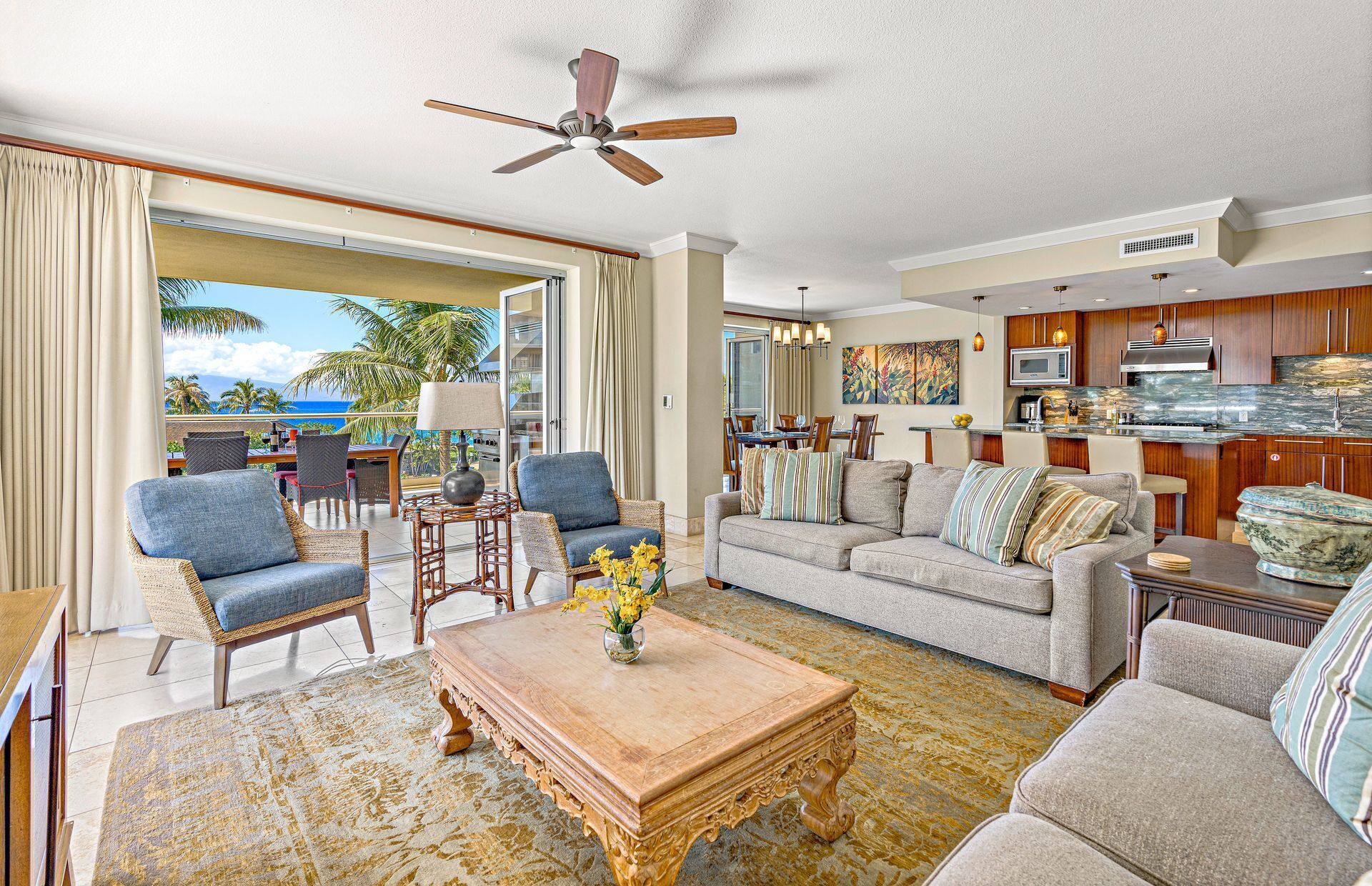 A spacious living area with a balcony overlooking the ocean, a dining area, and a kitchen with wooden cabinets and modern appliances.