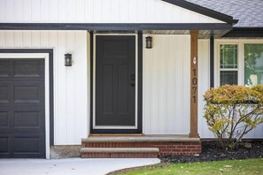 Een woonhuis met een zwarte voordeur, een garagepoort en een brievenbus.