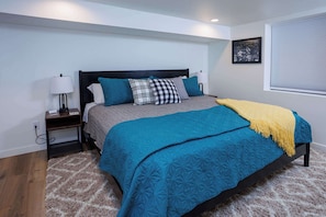 A bedroom with a bed, nightstand, lamp, and a framed picture on the wall. - Cheese Head Hideaway - Walk to Lambeau Field (Green Bay)