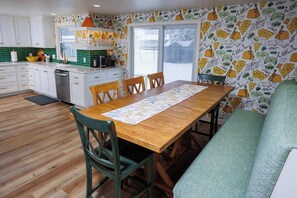 A kitchen with white cabinets, a wooden dining table, and a patterned wall.