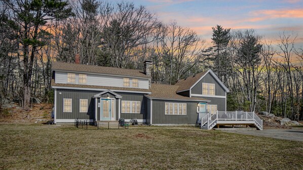 A two-story house with a front porch and a staircase leading to a deck. - Sunny Cottage (Biddeford)
