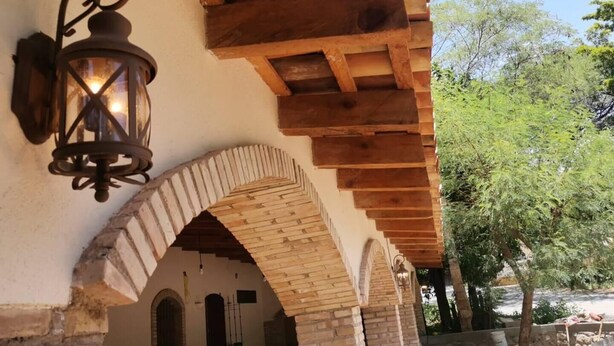 Un edificio rústico con techo de madera, un arco de ladrillo y un farol.