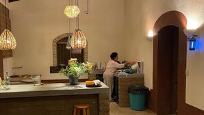 Una cocina con una isla central, lámparas colgantes y una persona lavando platos.
