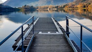 A wooden pier extending into a calm lake with mountains in the background.