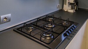 A kitchen with a gas stove, a coffee maker, and a black range hood.