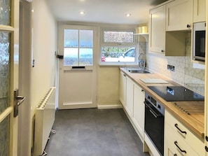 A compact kitchen with a window, a sink, and a stove. - Tranquil retreat in Keswick, Talcomb (Keswick)