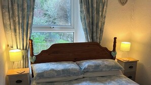 Ein Schlafzimmer mit einem Holz-Kopfteil, zwei Nachttischen mit Lampen und einem Fenster mit Vorhängen.