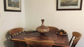 Ein Holztisch mit vier Stühlen, einer Vase und einem Teller mit Kiefernzapfen und einer Kürbis.
