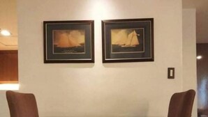 A dining area with a wooden table and four chairs. Two framed pictures are hung on the wall above the table. - Fernandina 88 Suites Residences (Quezon City)