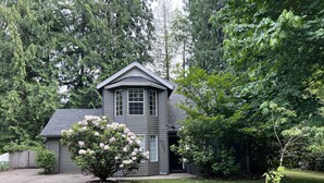 Een huis met twee verdiepingen, een grijze gevel en een kleine voortuin.