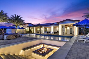A modern house with a swimming pool, outdoor seating, and a fire pit.