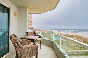 Enjoy the ocean view from this balcony with a table and two chairs.
