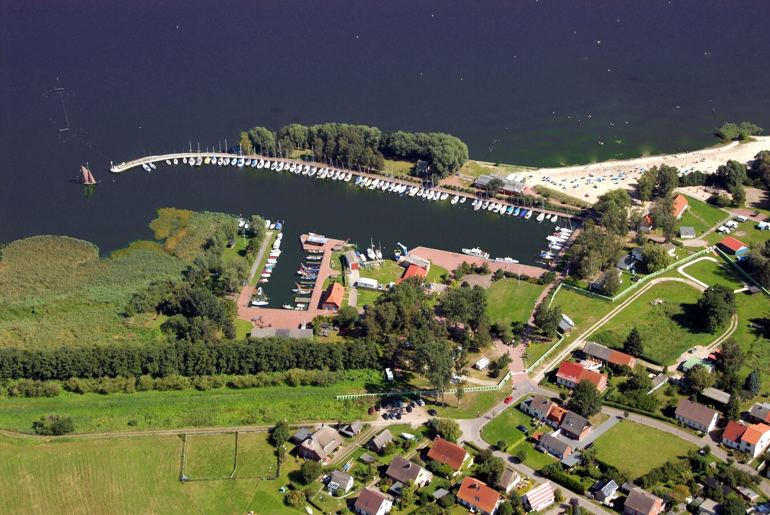 Eine Luftaufnahme einer Küstenregion mit einem Yachthafen, Booten und Wohnhäusern.