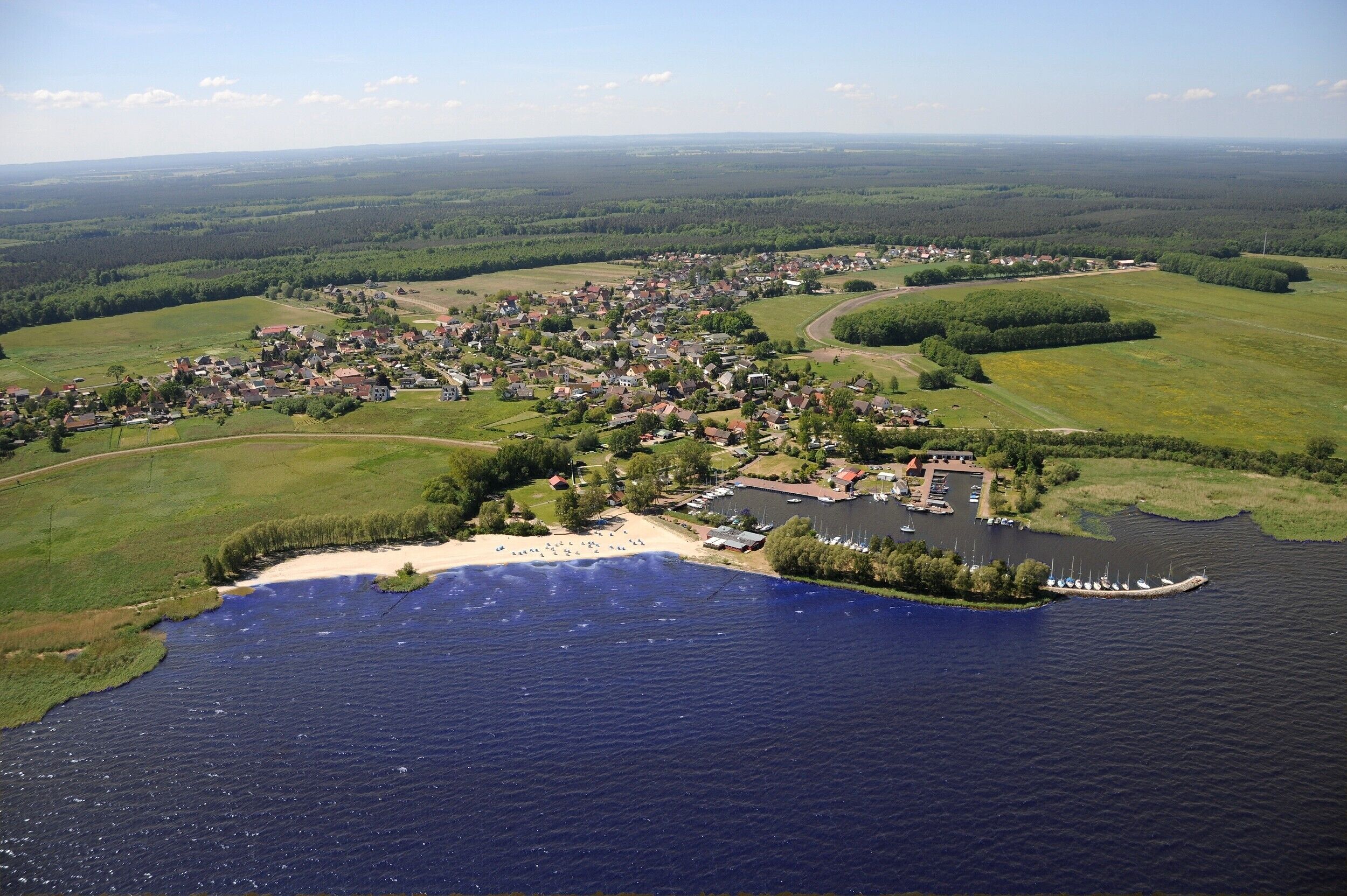 Eine Vogelperspektive auf eine an einem See gelegene Stadt mit Strand, Booten und einem Hafen.