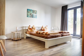 A modern bedroom with a large bed, a bedside table, a chair, and a window with curtains.