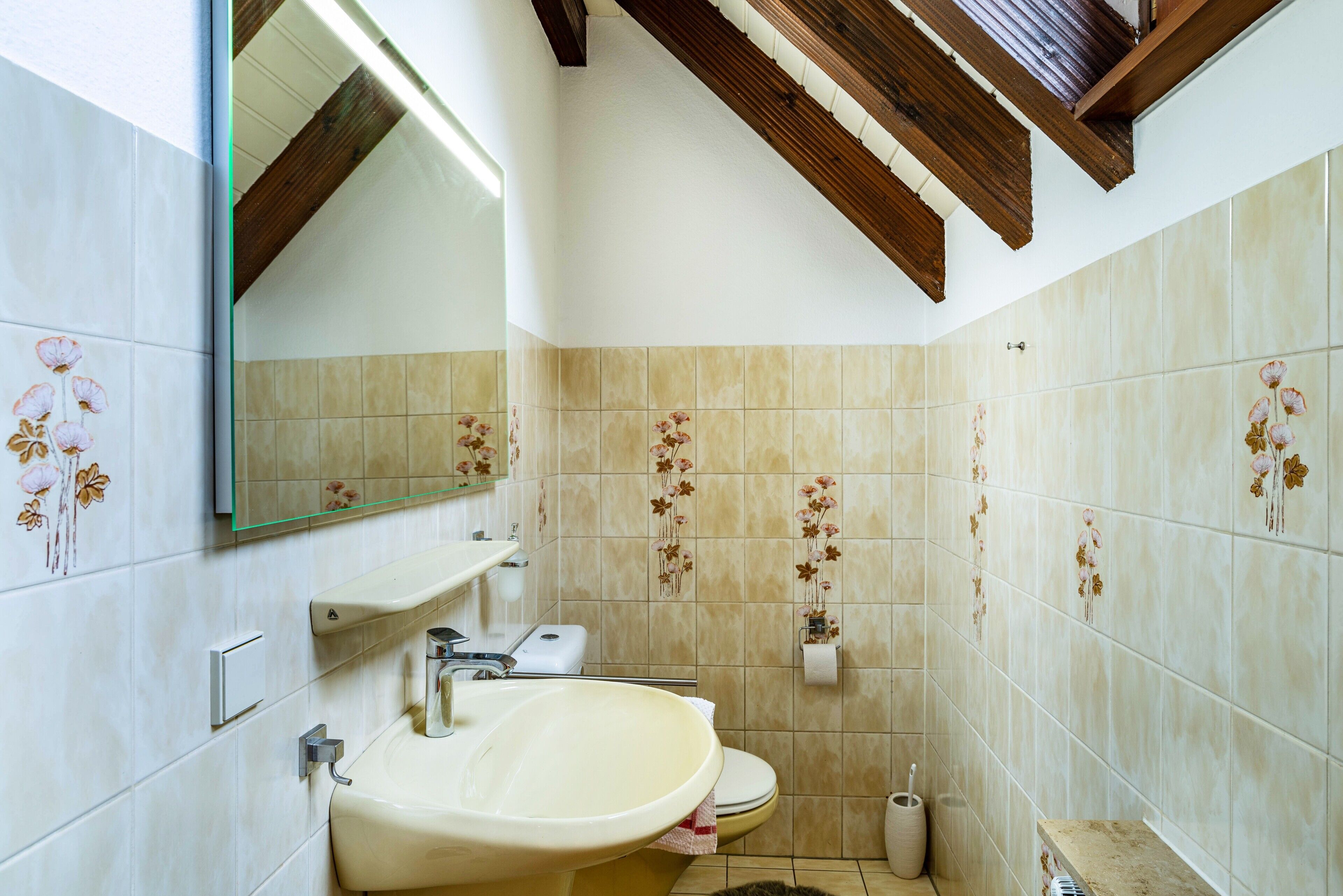 Een badkamer met een wastafel, toilet en spiegel.