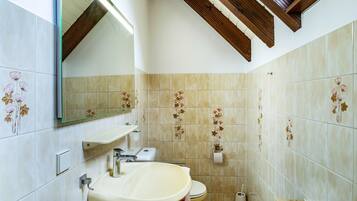 Een badkamer met een wastafel, toilet en spiegel.