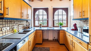 A kitchen with wooden cabinets, a dishwasher, a sink, and a window with a view. - Apartment 'Cheng One' with Private Terrace, Balcony, and Wi-Fi (Baden-Baden)
