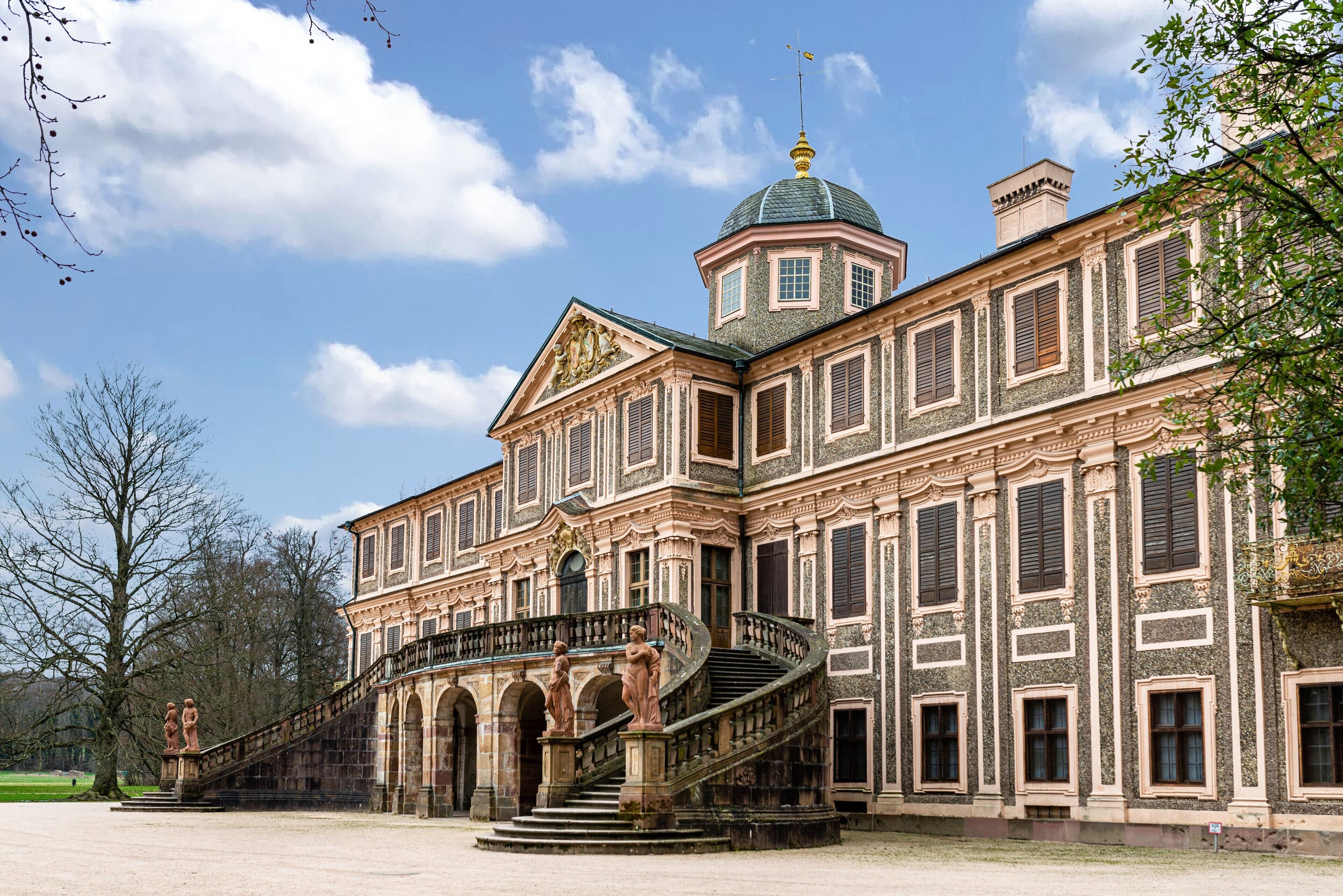 A historic building with a grand staircase, large windows, and a dome.