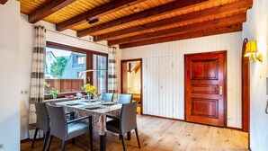 A dining area with a wooden ceiling, a dining table set for four, and a view of the outside. - Apartment 'Cheng One' with Private Terrace, Balcony, and Wi-Fi (Baden-Baden)