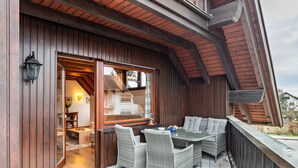 An outdoor patio with wicker furniture, a wooden deck, and a glass door leading to an interior space. - Apartment 'Cheng One' with Private Terrace, Balcony, and Wi-Fi (Baden-Baden)