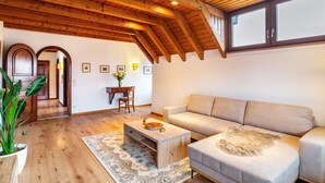A spacious living room with a wooden ceiling, a sofa, a coffee table, and a dining area with a table and chairs. - Apartment 'Cheng One' with Private Terrace, Balcony, and Wi-Fi (Baden-Baden)