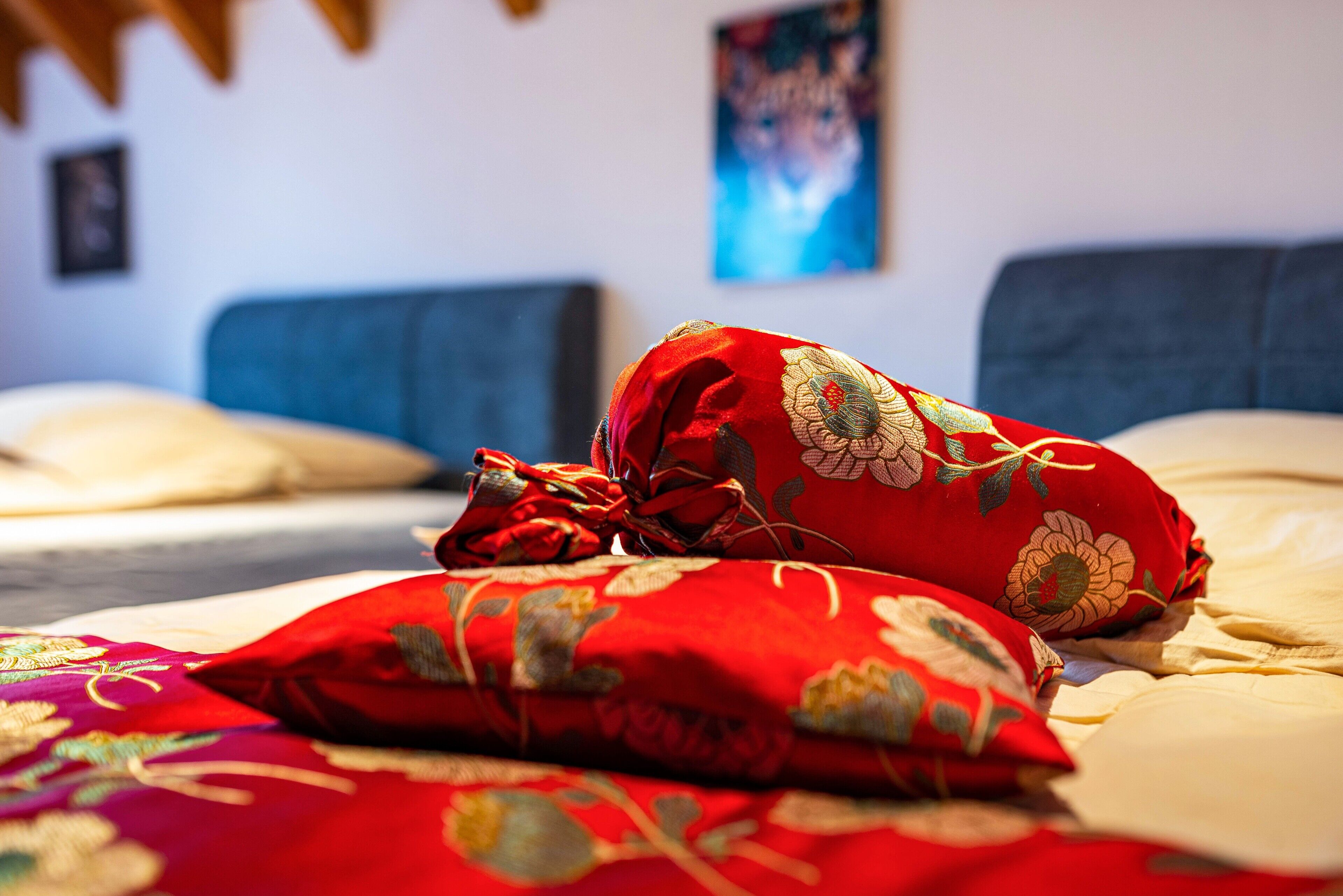 Ein Bett mit roten blumigen Kissen und einem blauen Kopfteil.