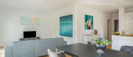 A modern living room with a sofa, a dining table, and artwork on the walls.