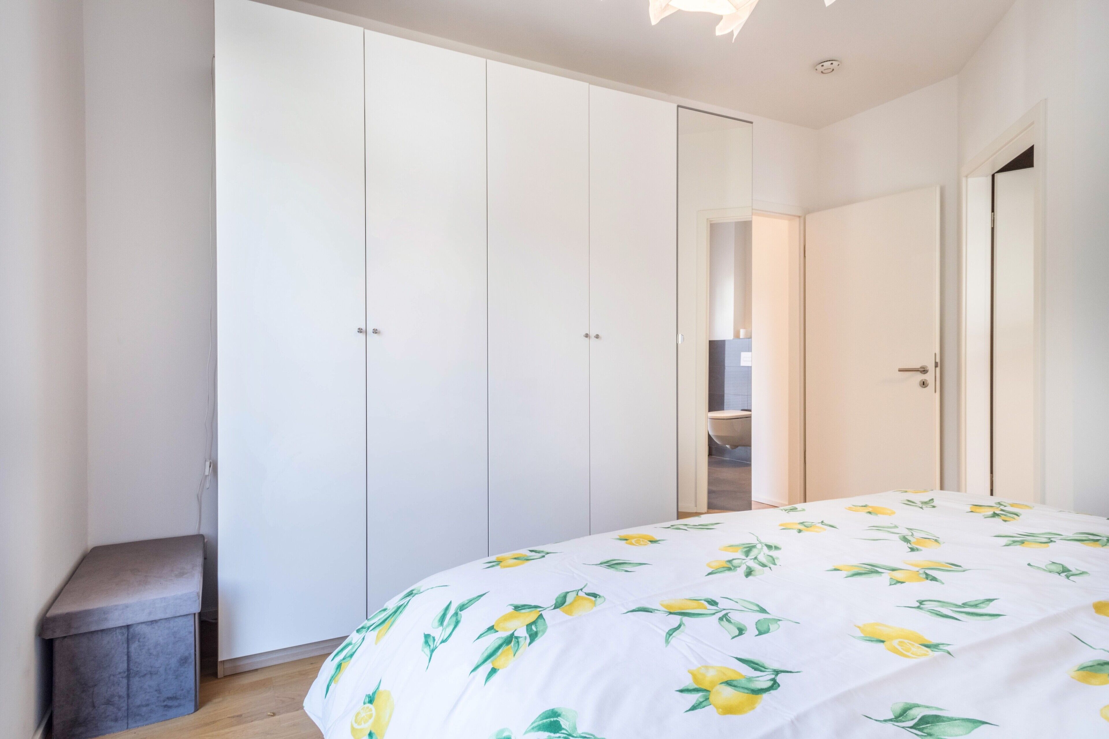 Un dormitorio con cama, armario y una banca.