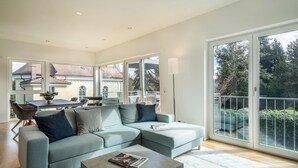 Ein modernes Wohnzimmer mit Ecksofa, Couchtisch und einem Essbereich mit Tisch und Stühlen.
